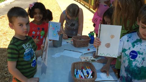 A group of children write and color in paper journals