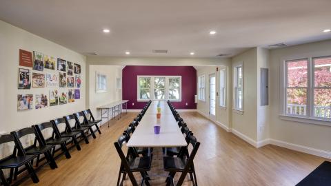 a view of a long room set up with a long table and chairs down the middle