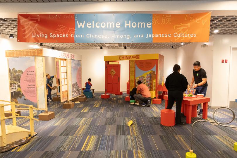 a pulled back view of a full museum gallery with a banner that reads, "Welcome Home"