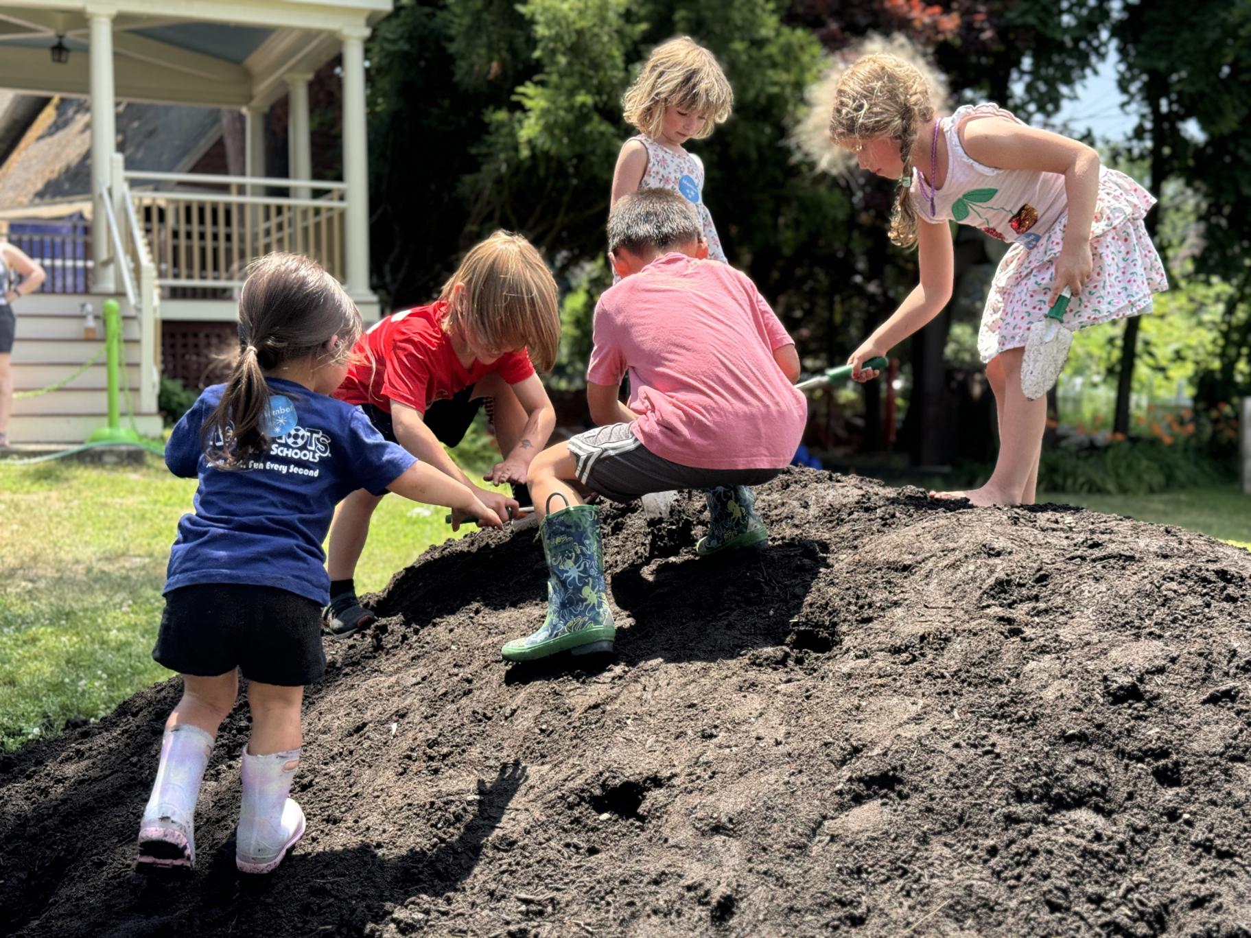 several children explore a giant pile of dirt together